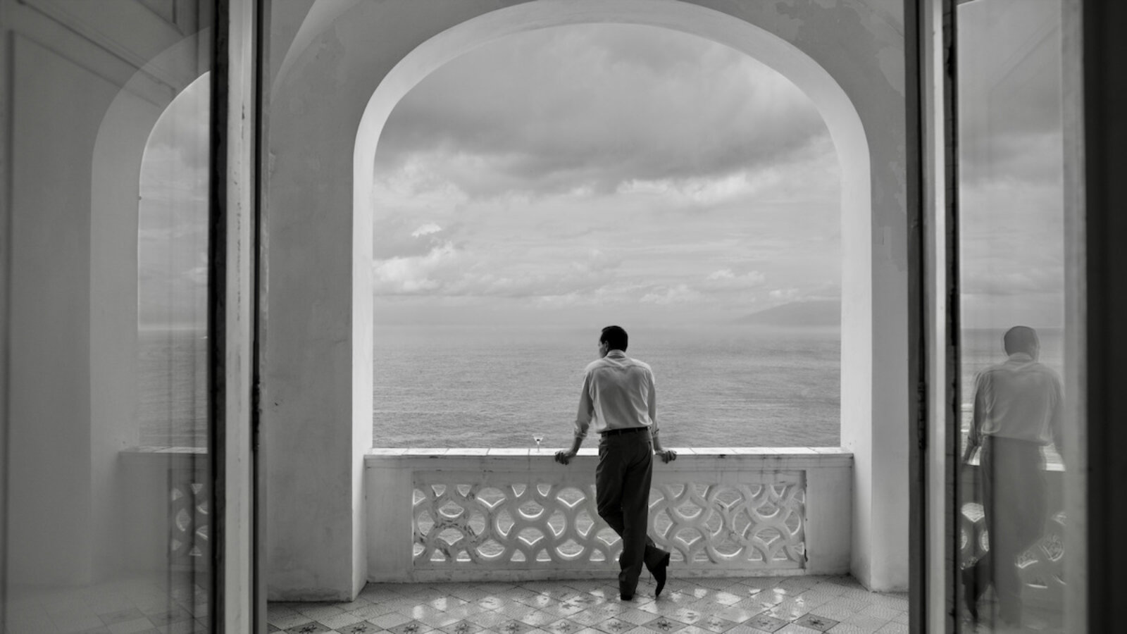 Andrew Scott als Tom Ripley in der Netflix-Serie Ripley. Er ist von hinten zu sehen, auf einem italienischen Balkon, und blickt aufs Meer.