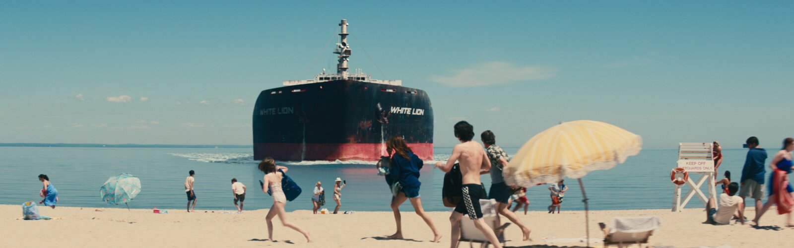Ein Tanker kracht in die Küste, an der Urlauber baden. Eine Szene aus Leave the World Behind.
