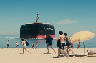 Ein Tanker kracht in die Küste, an der Urlauber baden. Eine Szene aus Leave the World Behind.
